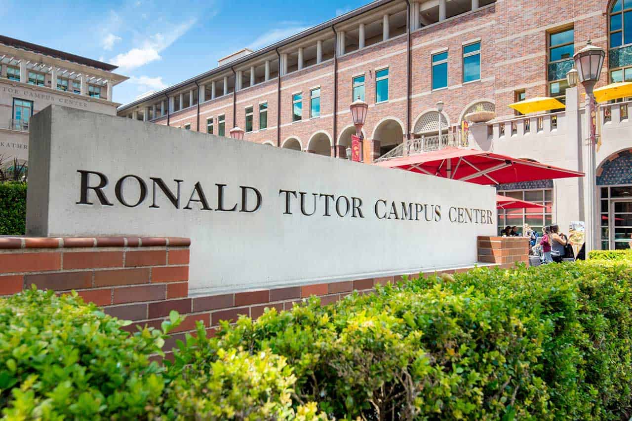 An entrance sign that reads Ronald Tutor Campus Center with outdoor furniture behind it