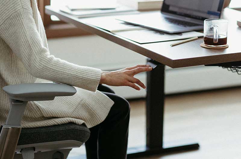 Furniture for Work from Home Spaces shows woman adjusting her desk