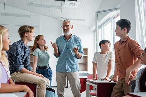 Mature teacher interacting with high school students in a group.