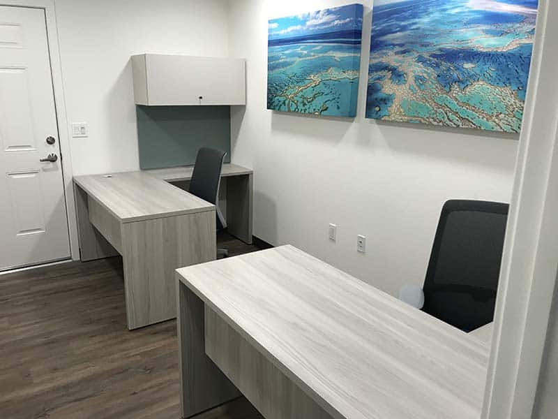 OBV office furnished with Haworth Planes L-shaped table, Haworth X-Series overhead storage with a tackable surface underneath and Haworth Soji Task Chairs
