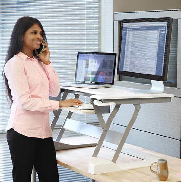 Woman working from an Ergotron WorkFit-T desk accessory in standing position.